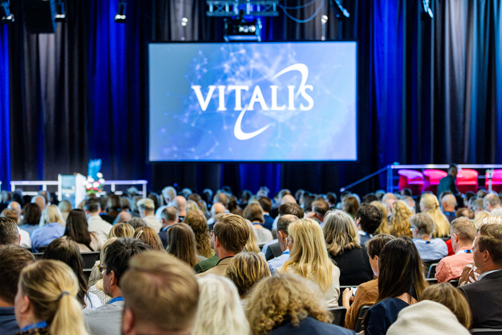 Konferenssal fylld med folk och en skärm med Vitalis logotyp